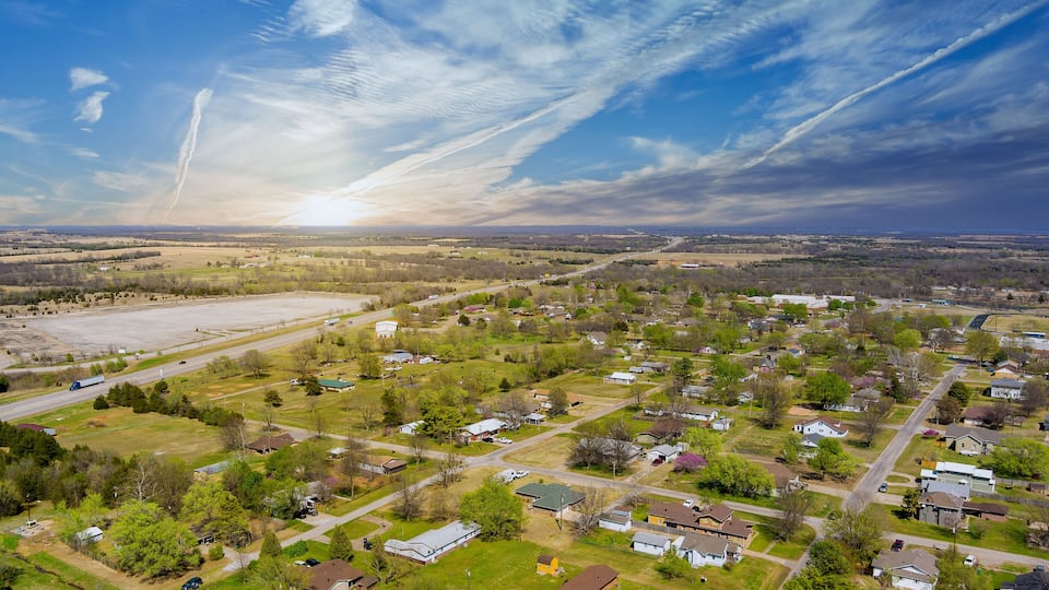 An aerial view of a suburban area with houses, roads, and open fields.
