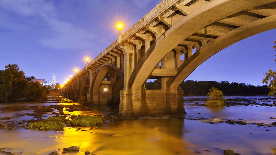 A bridge with multiple arches over a river at dusk.