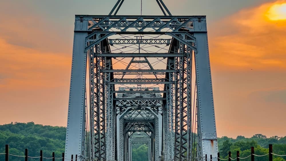 A railway bridge with a metal truss structure and tracks leading into the distance.