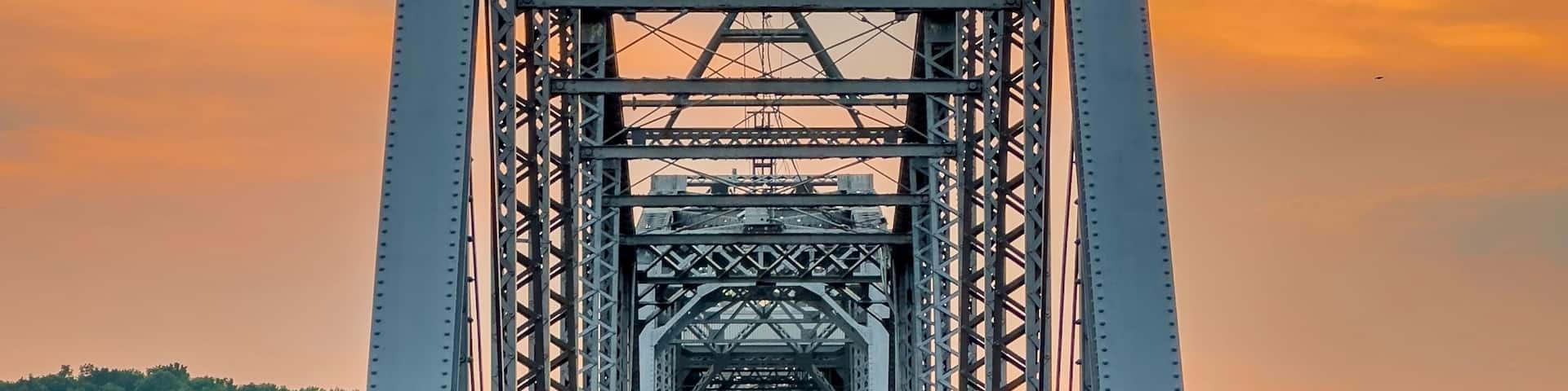 A railway bridge with a metal truss structure and tracks leading into the distance.