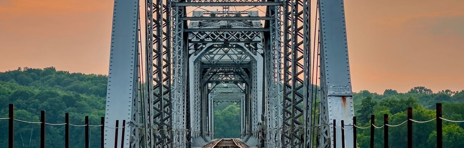 Un puente ferroviario con estructura de celosía metálica y vías que se extienden hacia la distancia.