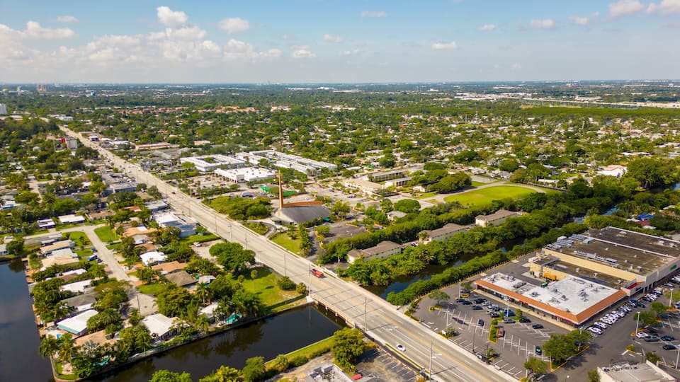 An aerial view of a city with a river, green spaces, and a bridge.