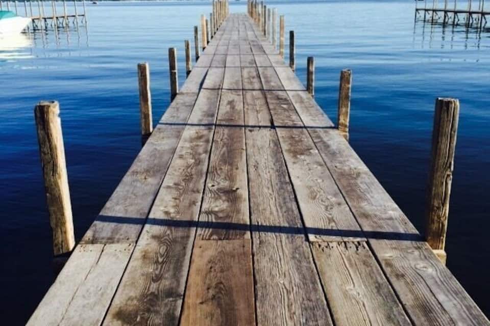 A wooden pier extending into calm water with a clear sky above.