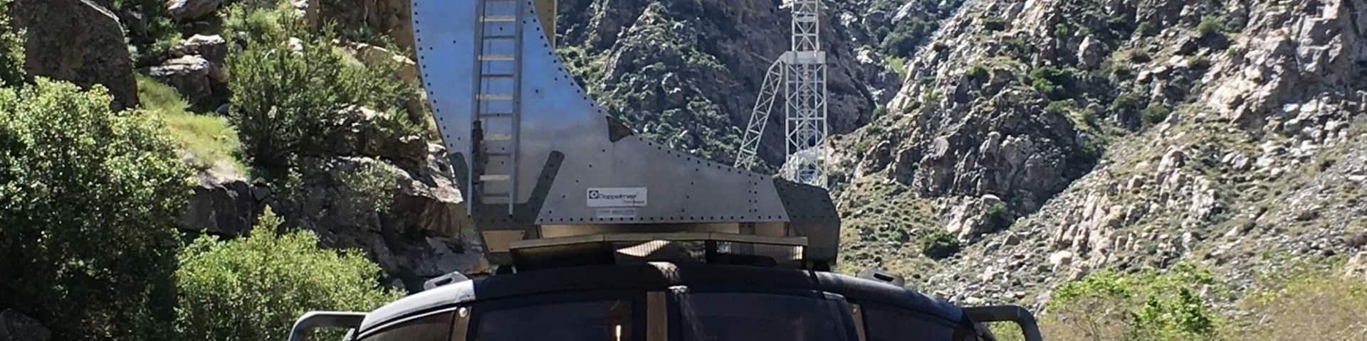 A cable car with 'Palm Springs' written on it, traveling over a mountainous landscape.