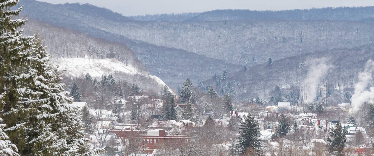 A snow-covered town nestled in a valley with mountains in the background.