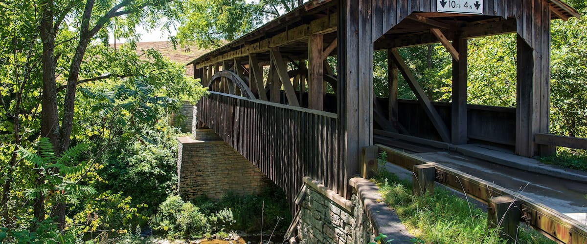 A wooden covered bridge with a clearance sign indicating a 10 ft 4 in height limit.