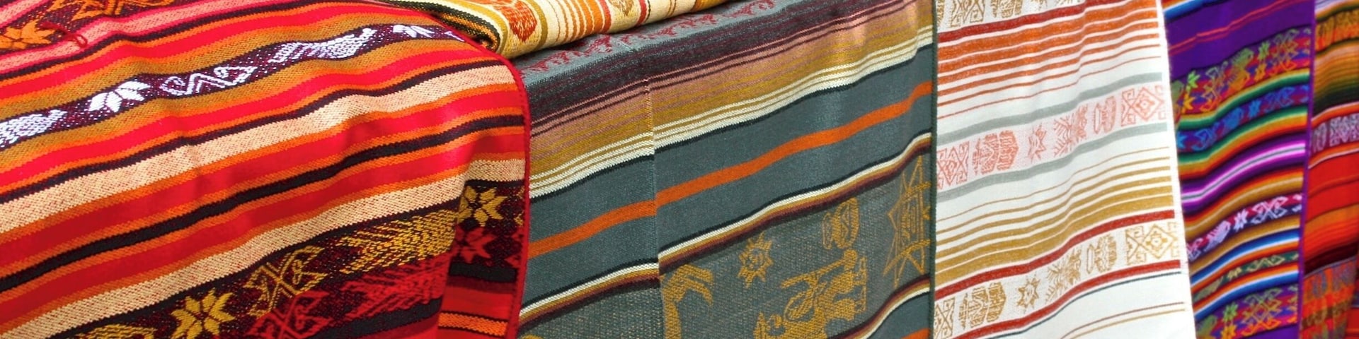 Una variedad de textiles coloridos exhibidos sobre una mesa.