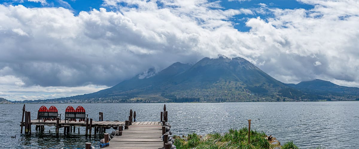 A wooden pier extending into a lake with mountains in the background.