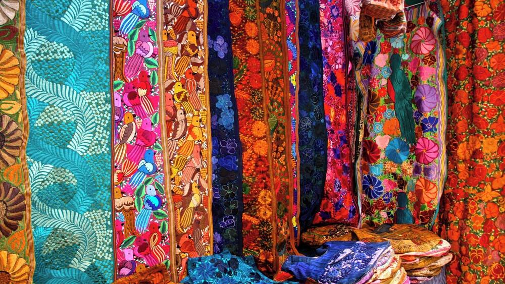A display of colorful, intricately embroidered textiles.