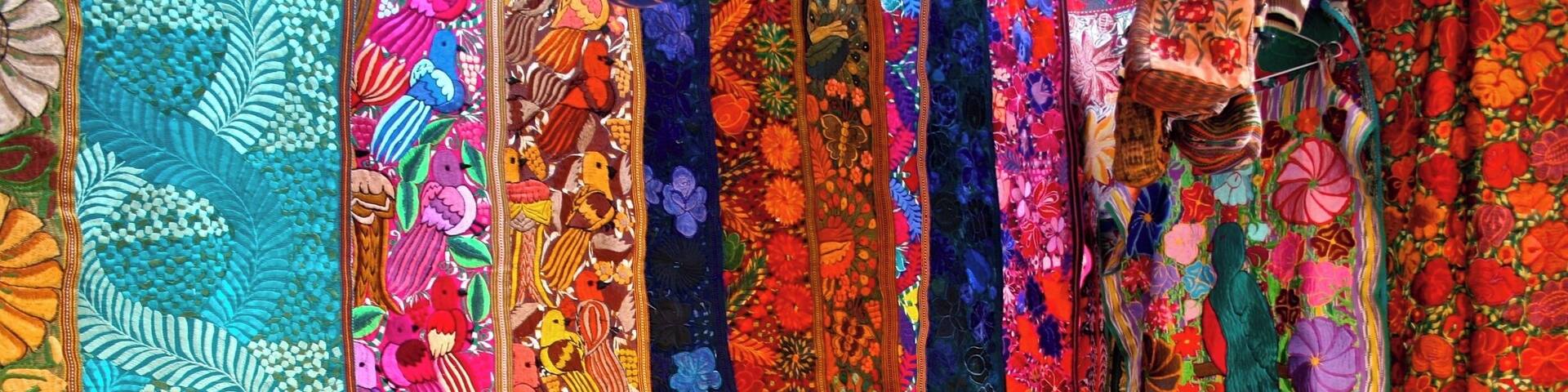 A display of colorful, intricately embroidered textiles.