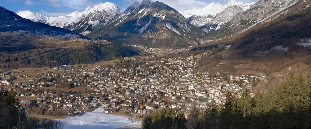 A town nestled in a valley with snow-capped mountains in the background.
