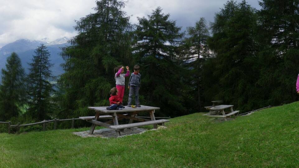 panoramic photo of mountain landscape in Valtellina, children play in place for picnics, mountains in spring, path, Bormio, Lombardy, Italy