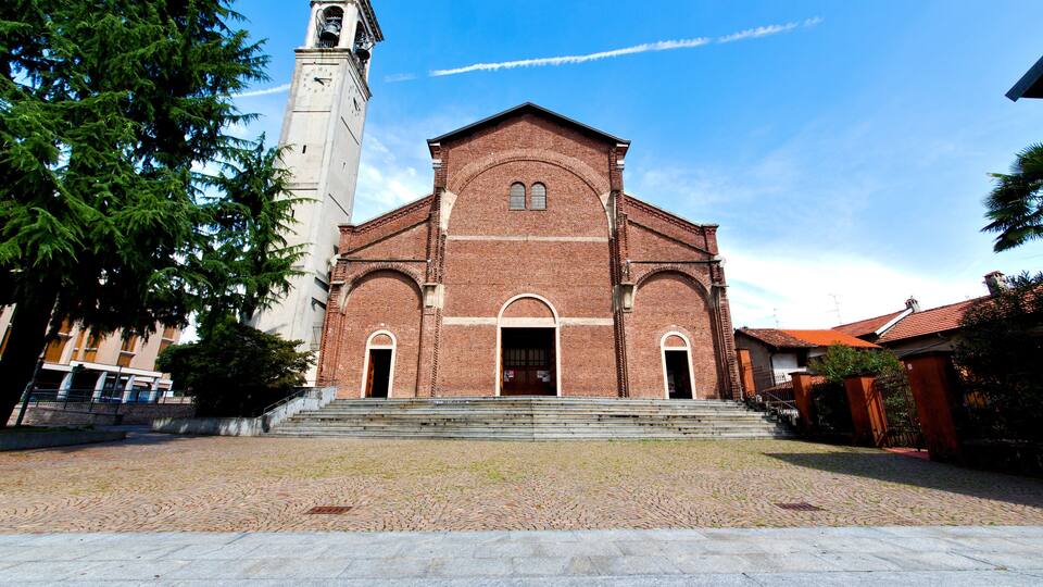 A historic church with a bell tower and a cobblestone courtyard.