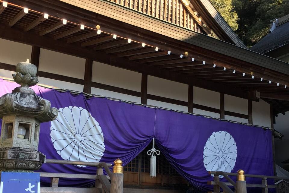 A traditional Japanese building with a purple entrance canopy, stone steps, and a stone lantern.