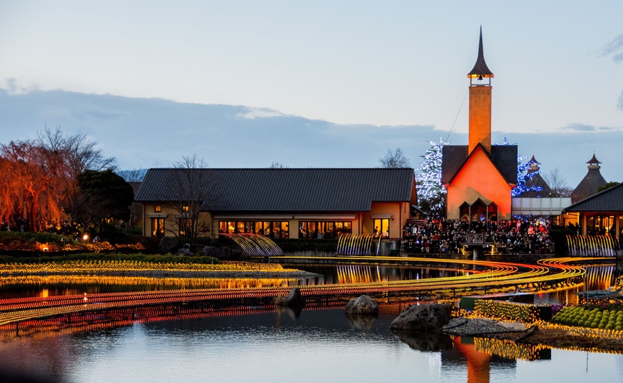 A riverside view with illuminated pathways, a church, and a traditional building.