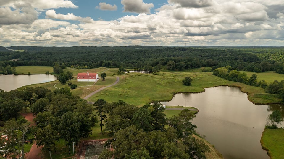A rural landscape with a large lake, a red-roofed building, and surrounding greenery.