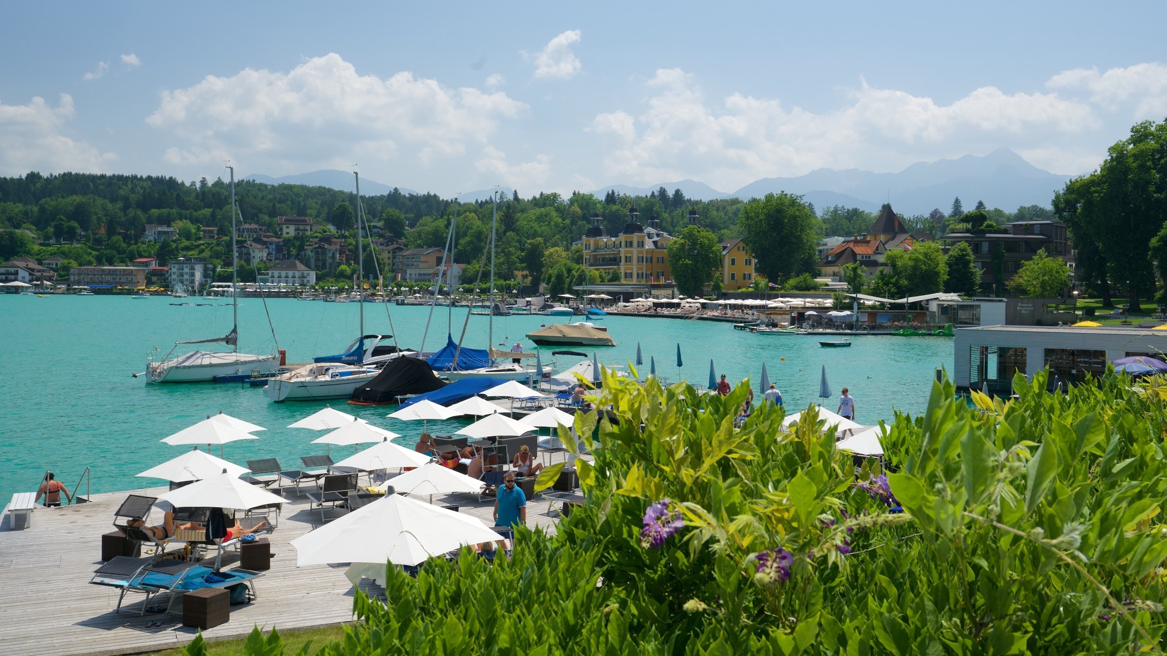 A marina with boats, umbrellas, and people.