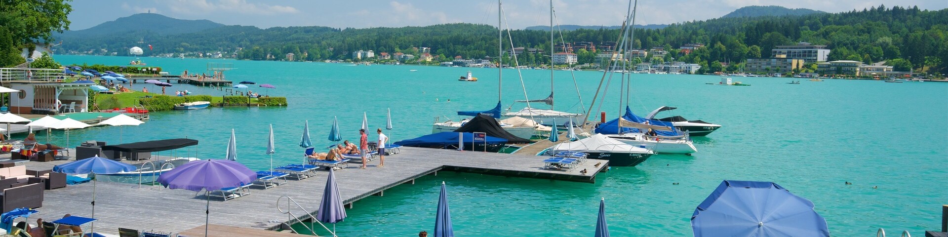 A marina with boats, a dock, and a grassy area with lounge chairs.