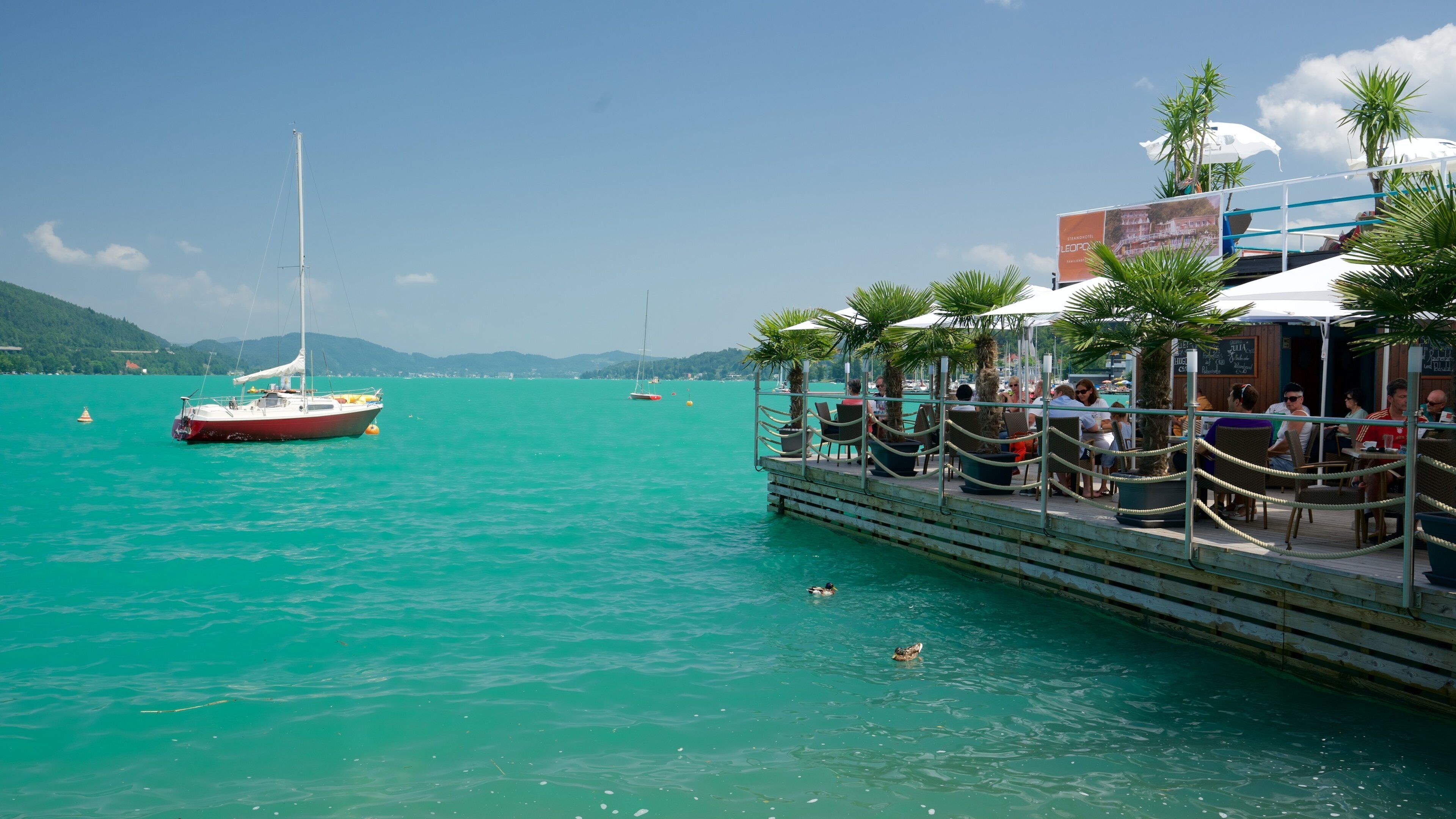 A waterfront restaurant with outdoor seating overlooking turquoise waters.