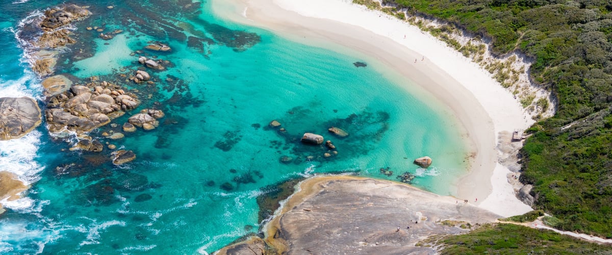 A coastal landscape with turquoise waters, white sandy beaches, and rocky outcrops.