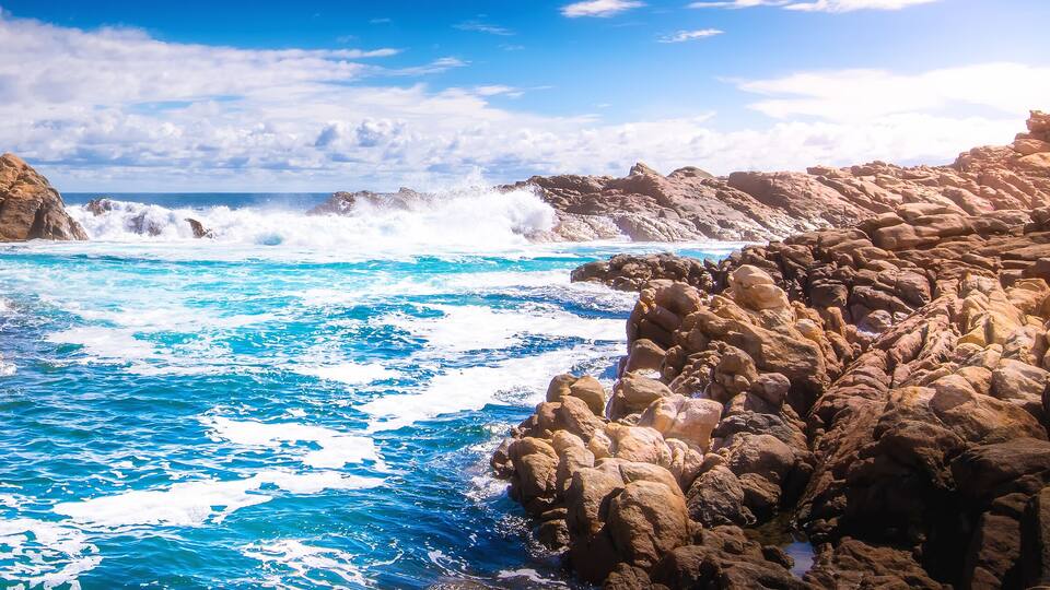 A rocky coastline with waves crashing against the rocks.