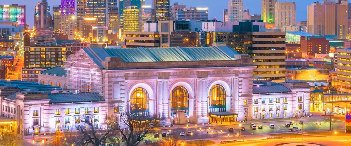 A cityscape with illuminated skyscrapers and a historic building with arched windows.