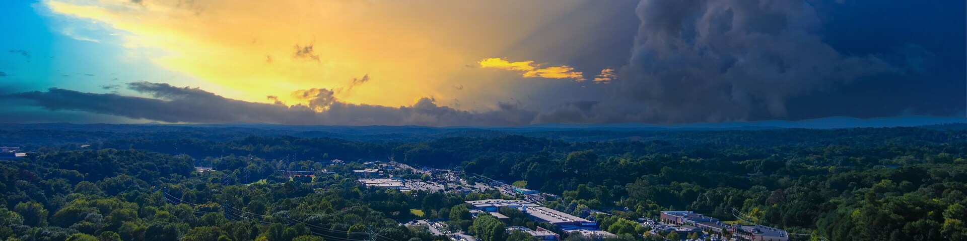 an aerial shot of the vast miles of lush green trees and grass with buildings nestled among the trees and powerful clouds at sunset at Etowah River Park in Canton Georgia USA