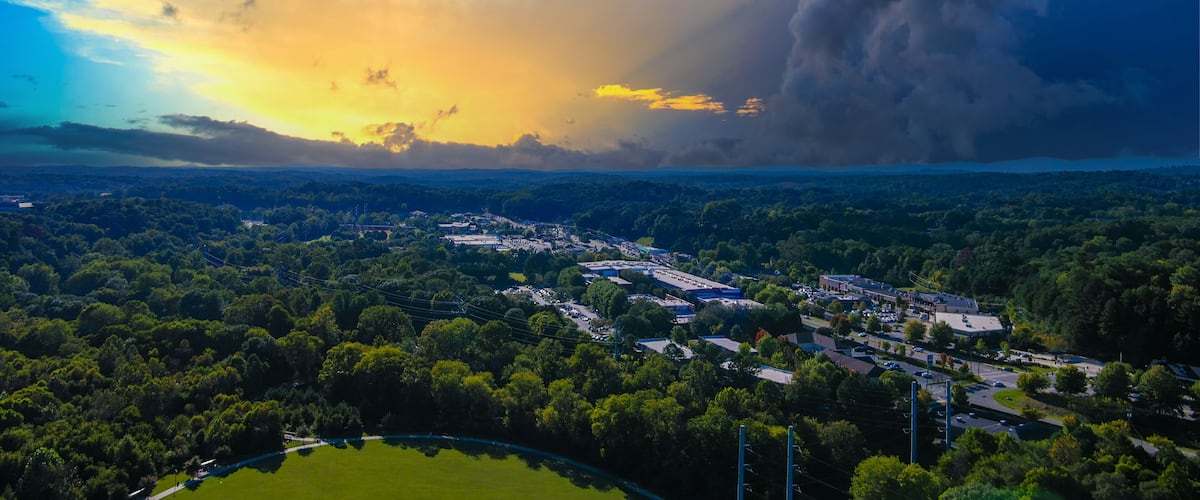 an aerial shot of the vast miles of lush green trees and grass with buildings nestled among the trees and powerful clouds at sunset at Etowah River Park in Canton Georgia USA