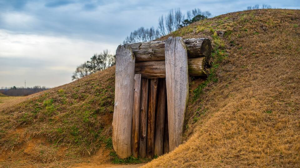 A wooden structure on a hillside with a dirt path leading up to it.