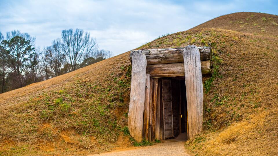 A wooden structure on a hillside with a dirt path leading to it.