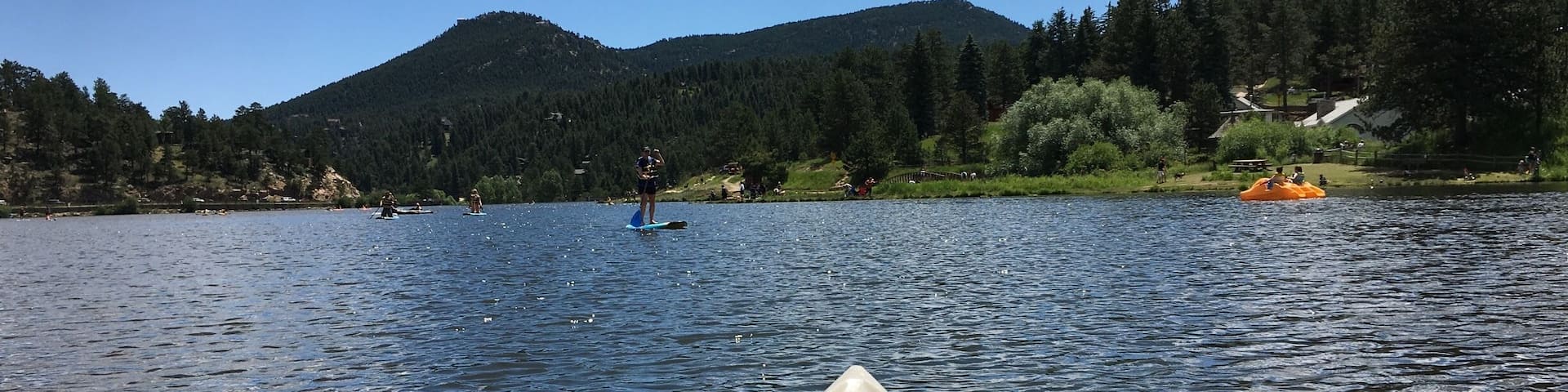 A kayak on a calm lake with mountains in the background and a partly cloudy sky.