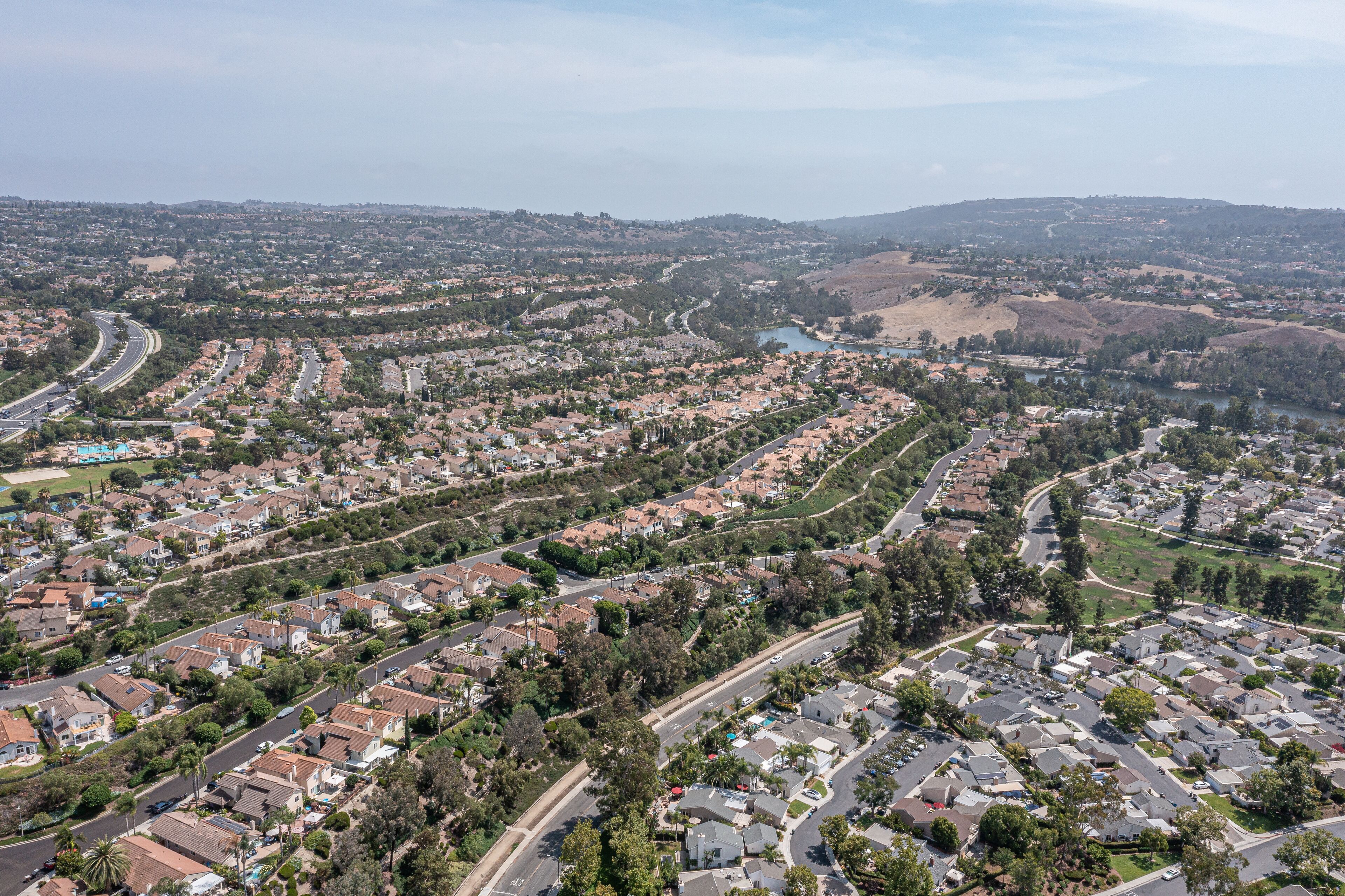 Aerial view of a southern California coastal community on a hill with a community lake in the background