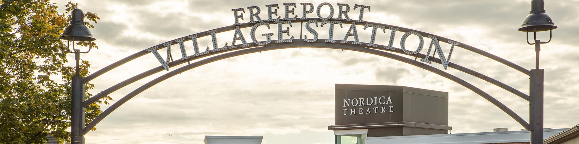 The entrance to Freeport Village Station with signs for Nordica Theatre, Brooks Brothers, and other local businesses.