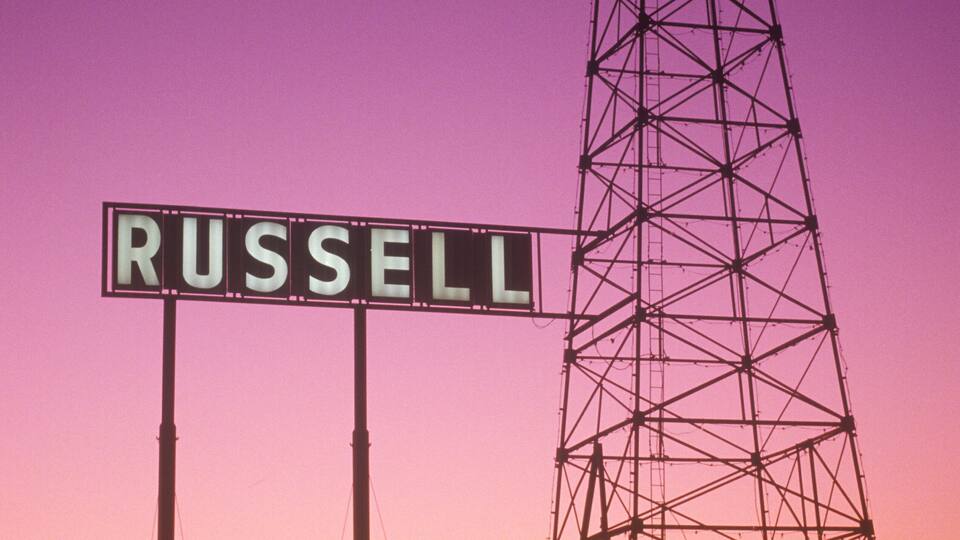 A power transmission tower with the sign 'RUSSELL' against a sunset sky.