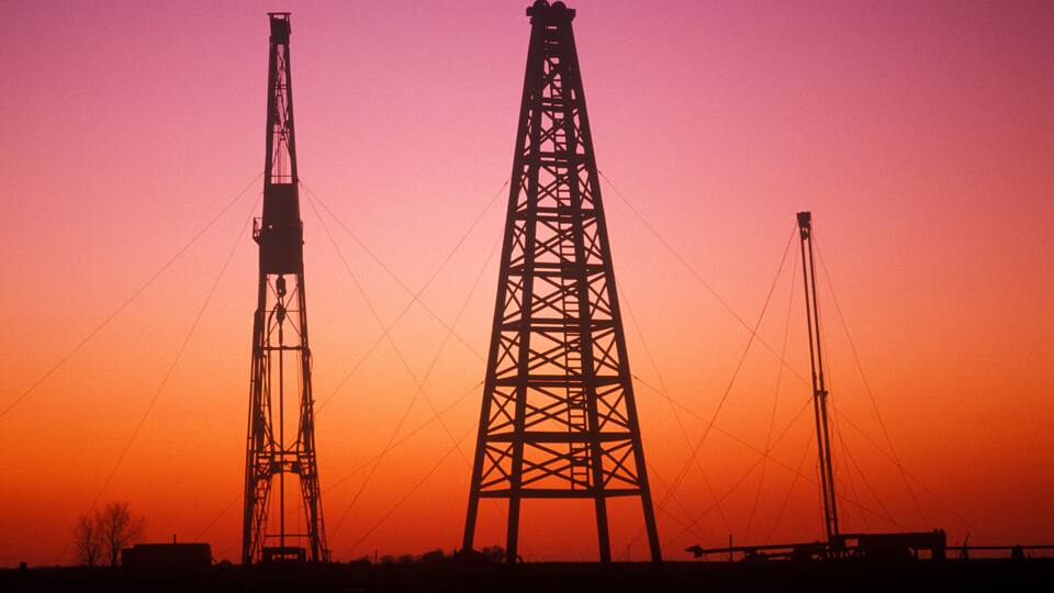 Two large power transmission towers silhouetted against a sunset sky.