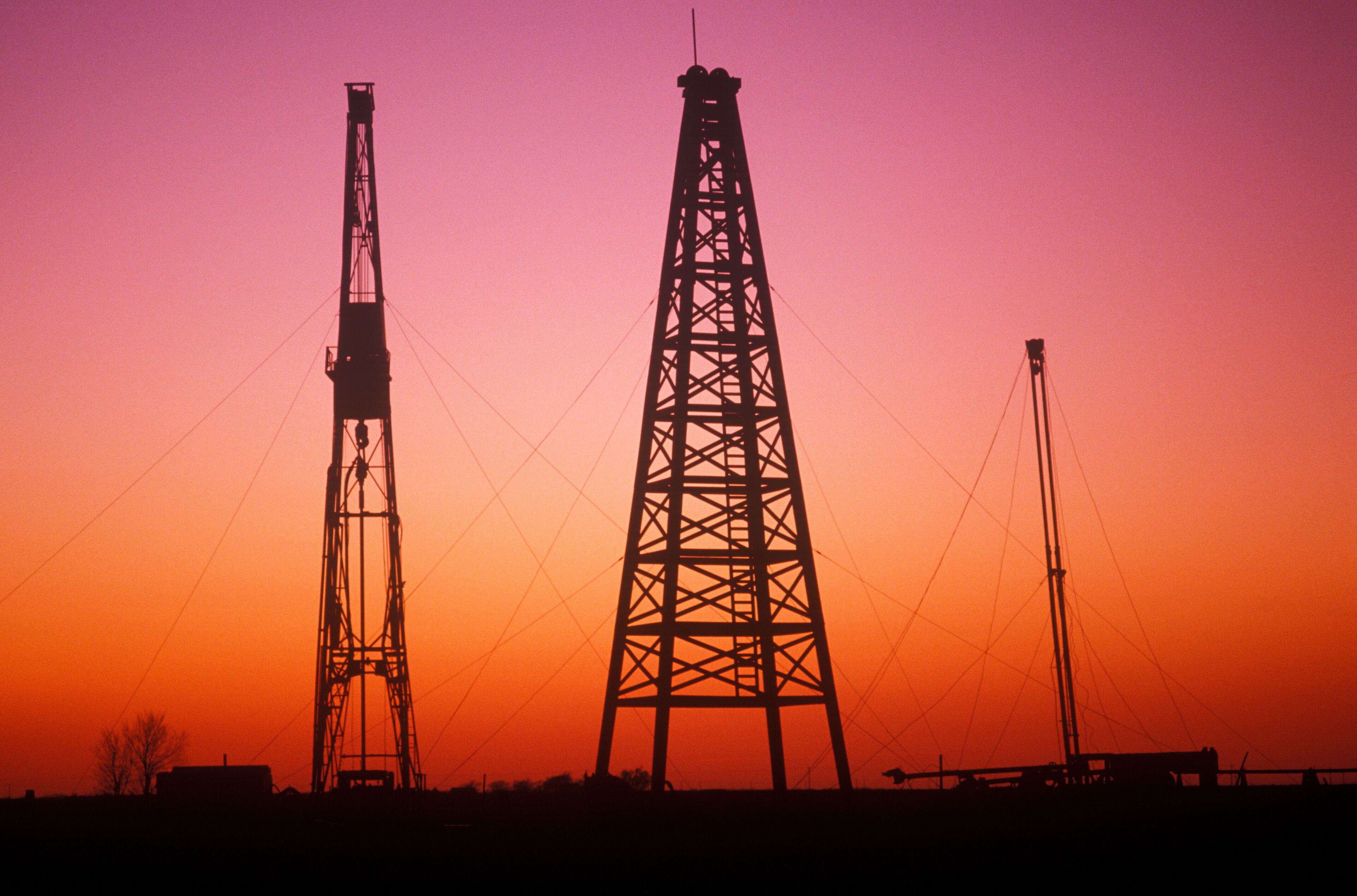 Two large power transmission towers silhouetted against a sunset sky.