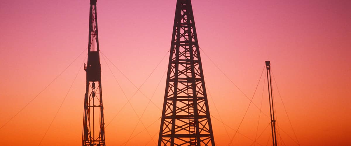 Two large power transmission towers silhouetted against a sunset sky.
