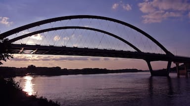 Uma ponte sobre um rio com o sol se pondo ao fundo.