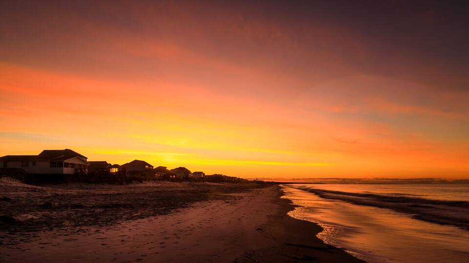A beach with houses at sunset.