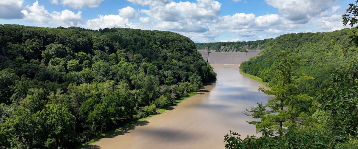 Mt Morris Dam in New York State on Genesse River at Letchworth State Park with blue sky and clouds in a beautiful countryside landscape with green trees in summer season