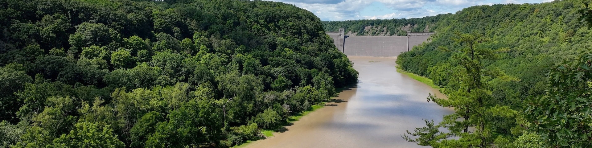 Mt Morris Dam in New York State on Genesse River at Letchworth State Park with blue sky and clouds in a beautiful countryside landscape with green trees in summer season