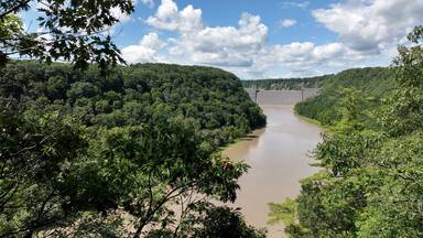Mt Morris Dam in New York State on Genesse River at Letchworth State Park with blue sky and clouds in a beautiful countryside landscape with green trees in summer season