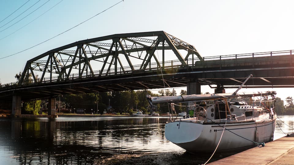A bridge over a river with a boat docked on the right.