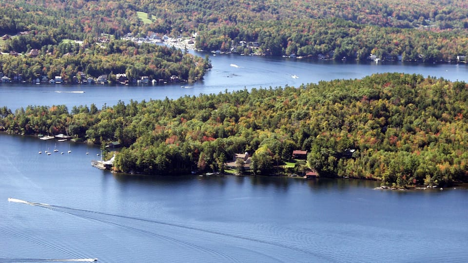 A lake surrounded by dense forests and small houses.