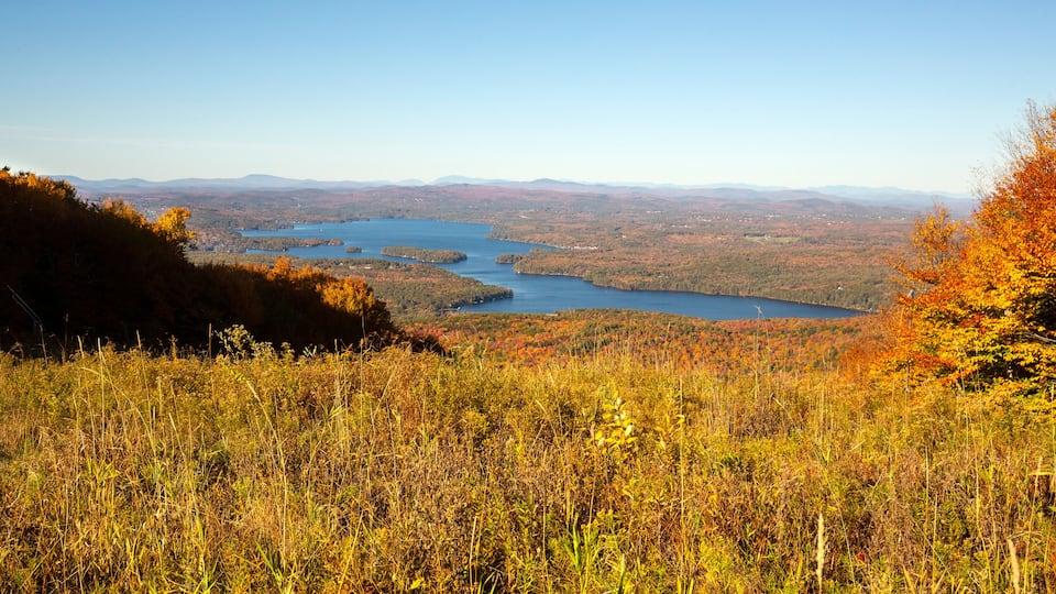 A lake surrounded by autumn foliage and distant mountains.