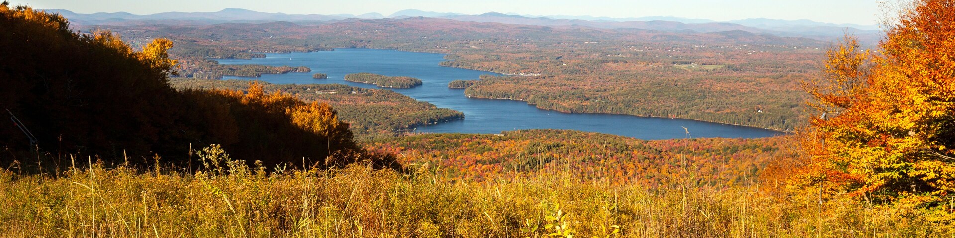 A lake surrounded by autumn foliage and distant mountains.