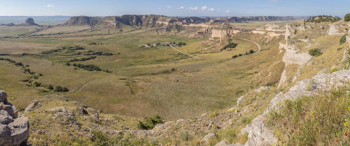 A rugged landscape with a winding road, rocky outcrops, and distant hills.