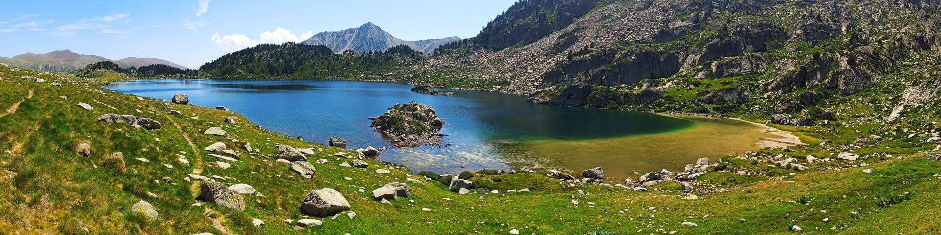 A mountainous landscape with a lake, rocky terrain, and a clear sky.