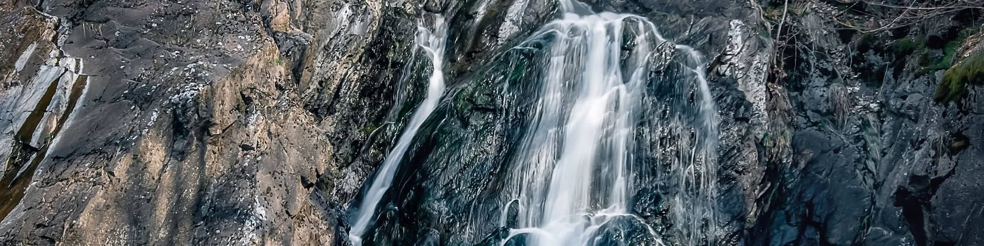 A waterfall cascading over rocks in a forested area.