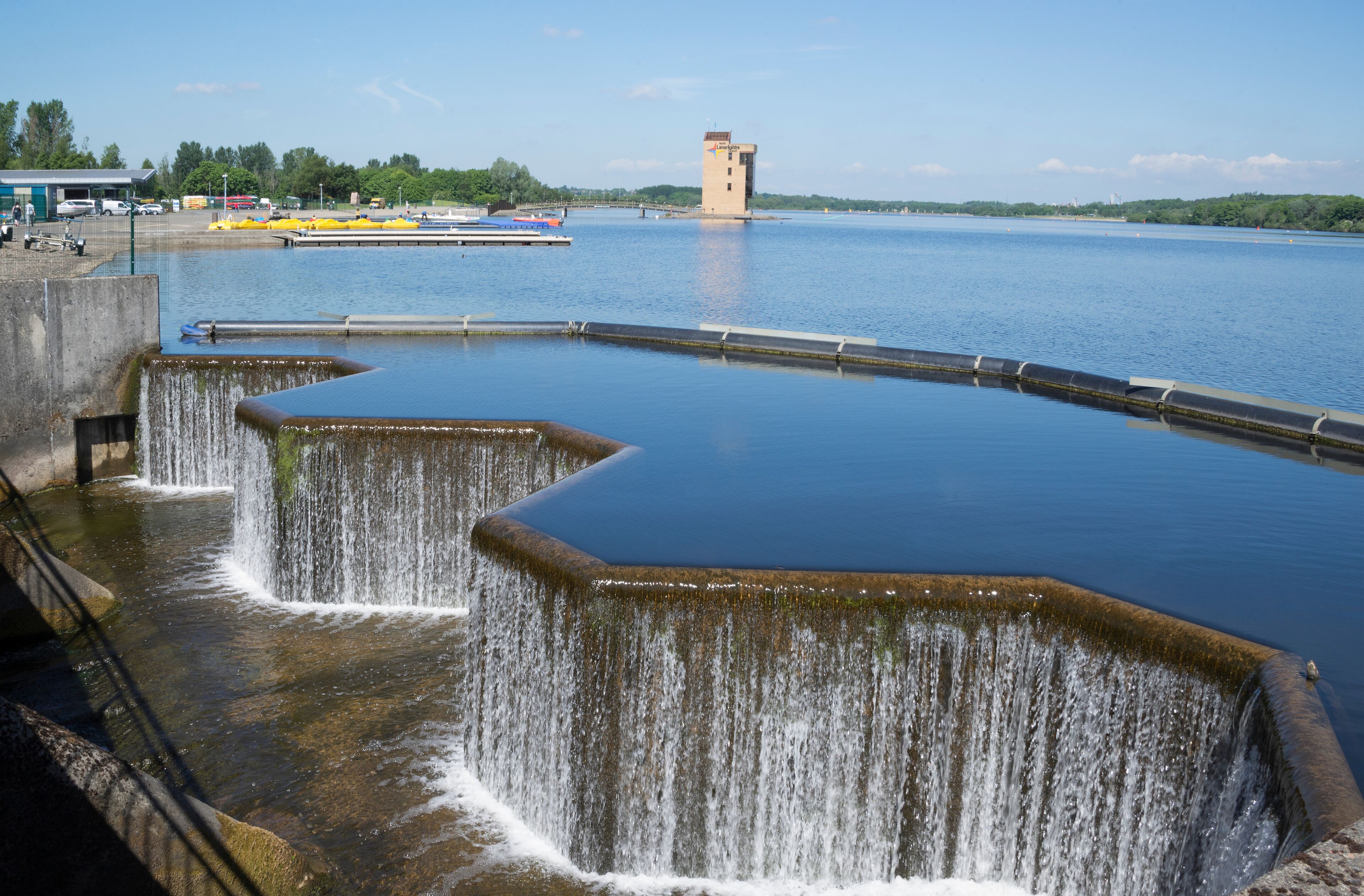 A dam with multiple spillways releasing water into a calm river.